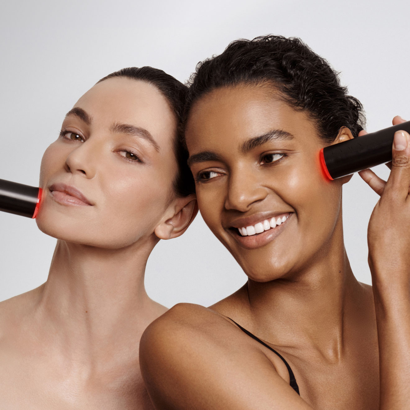 Dos mujeres aplicandose el lyma laser 500 mw en la piel una tie la piel clara con el pelo castaño recogido y la otra tiene la piel mas oscura y el pelo negro, demostrando que Lyma es apto para todo tipos de pieles. las dos mujeres tienen expresión facial de felicidad